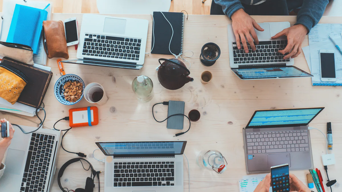Mesa de trabajo vista desde arriba con varias notebooks, teléfonos, cuadernos y tazas
